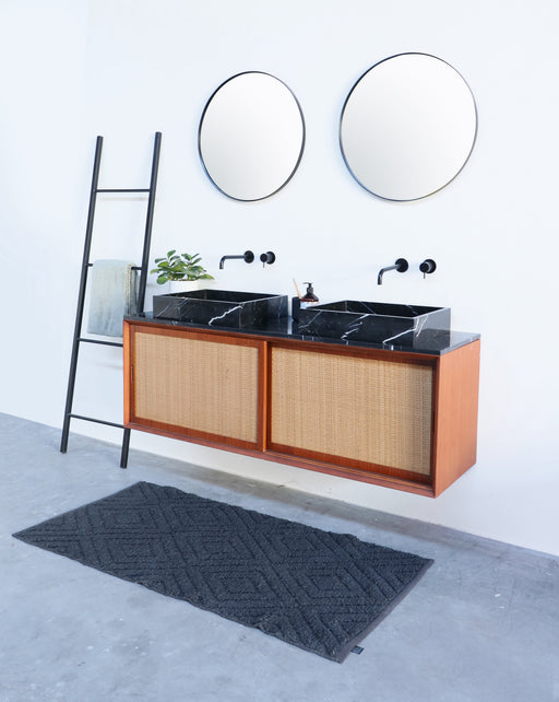 Zwart marmeren lavabo op rotan badkamerkast alt