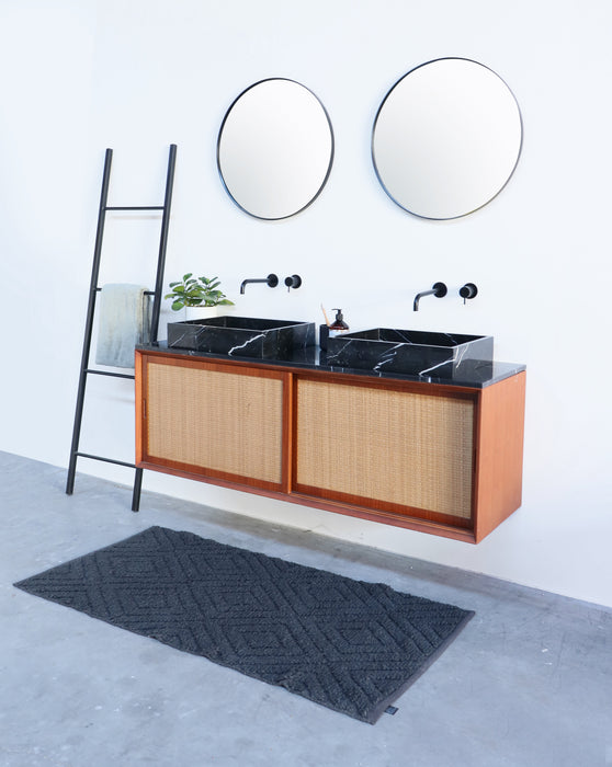 Zwart marmeren lavabo op rotan badkamerkast alt